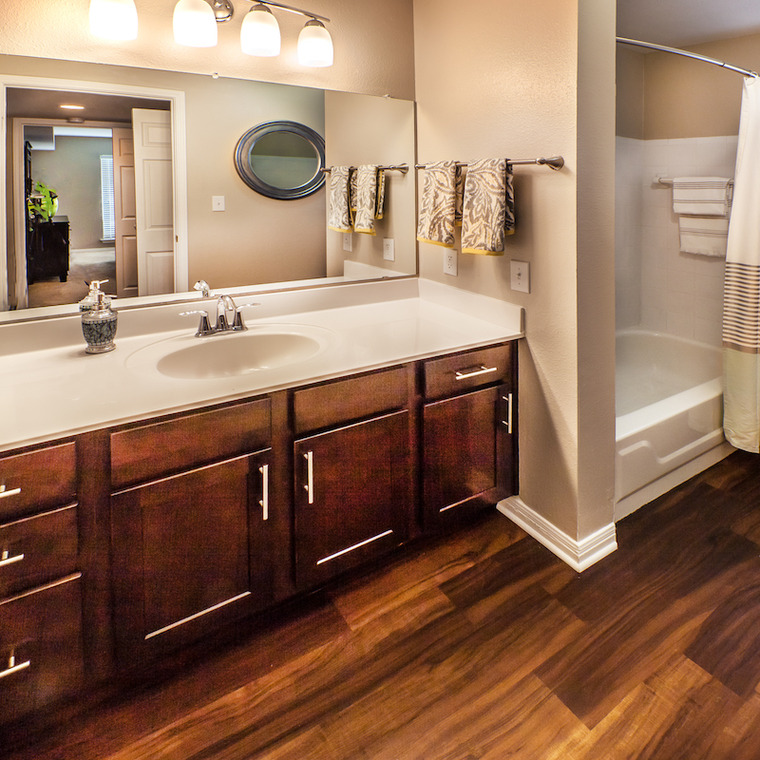 Bathroom with earth tones, dard wood laminate flooring, and dark wood vanity